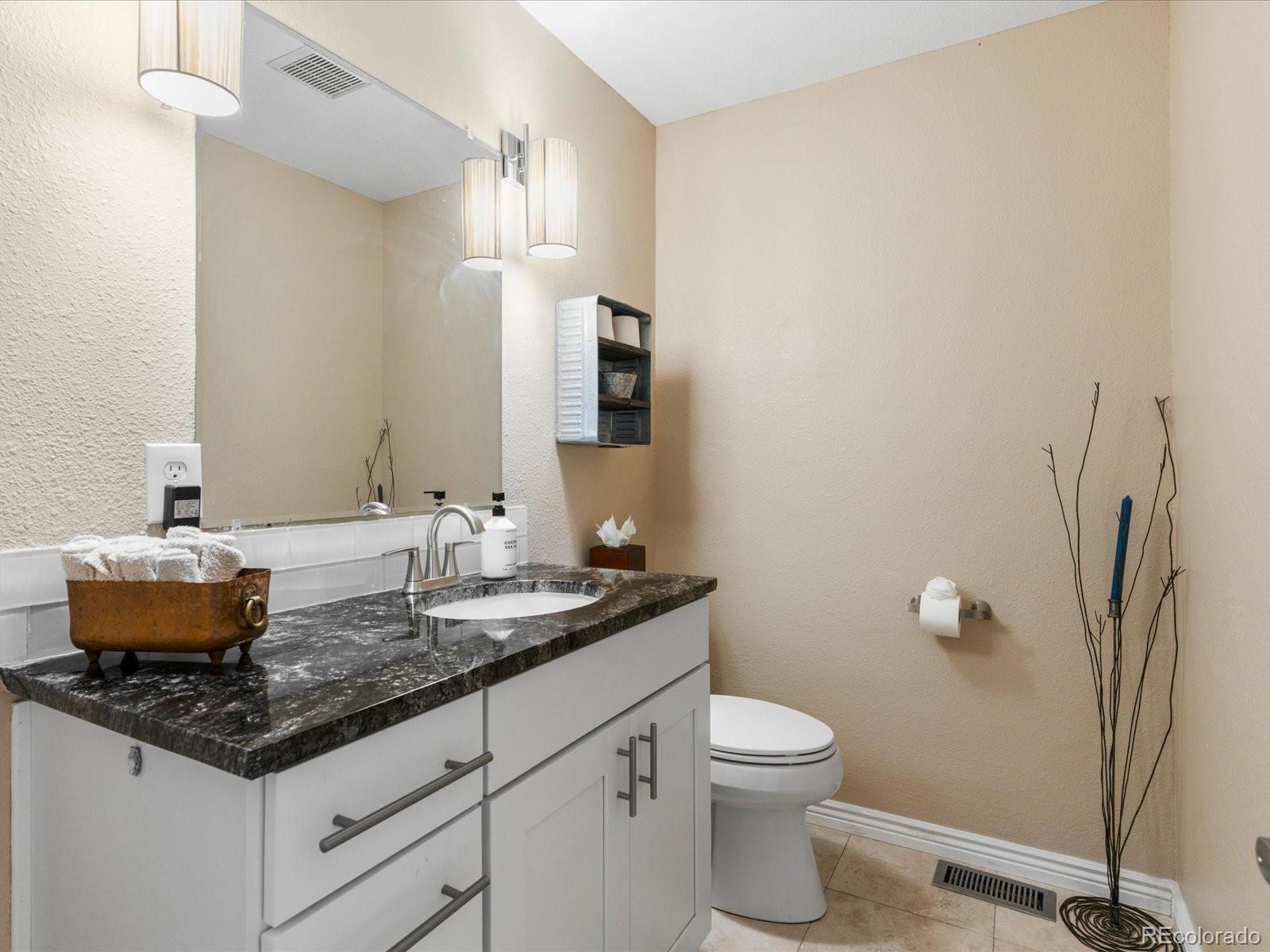 9323 Notts Court Lone Tree, CO 80124 - Photo 20 of 45 a bathroom with a granite countertop sink a toilet and a mirror