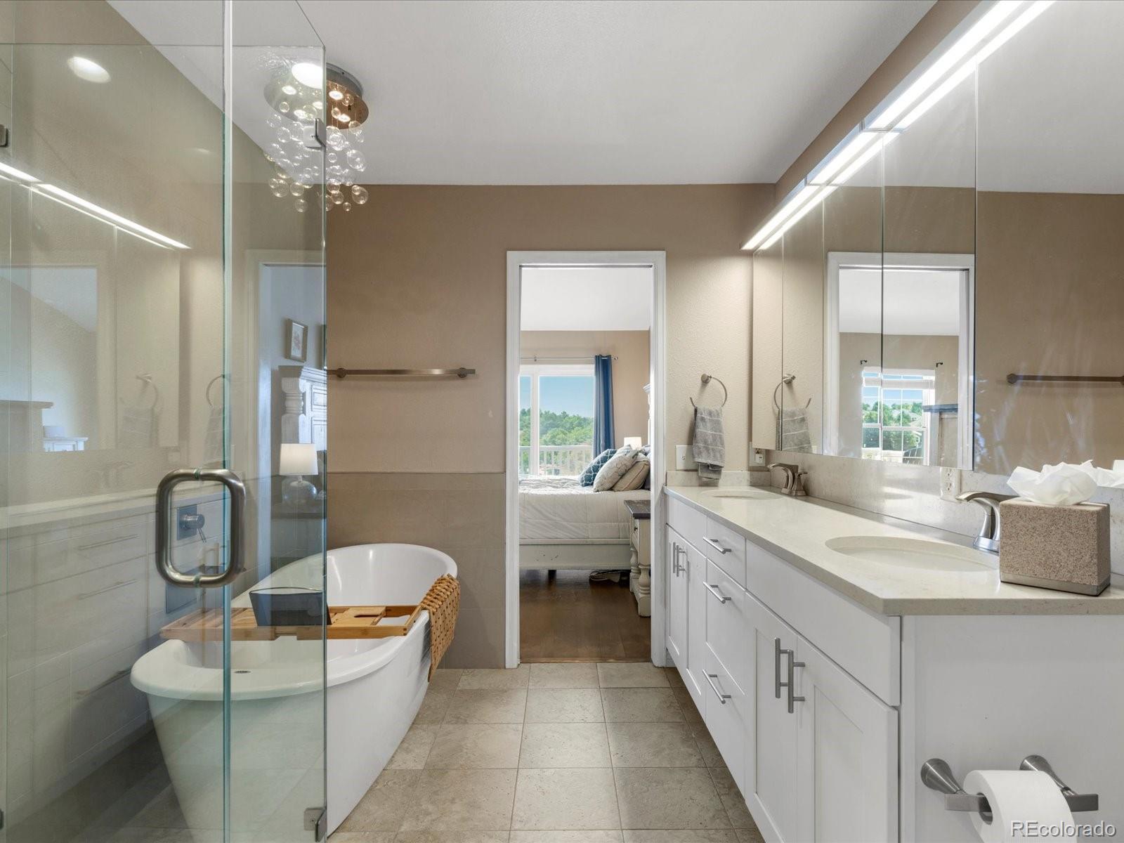 9323 Notts Court Lone Tree, CO 80124 - Photo 25 of 45 a bathroom with a granite countertop sink a large mirror and a bathtub