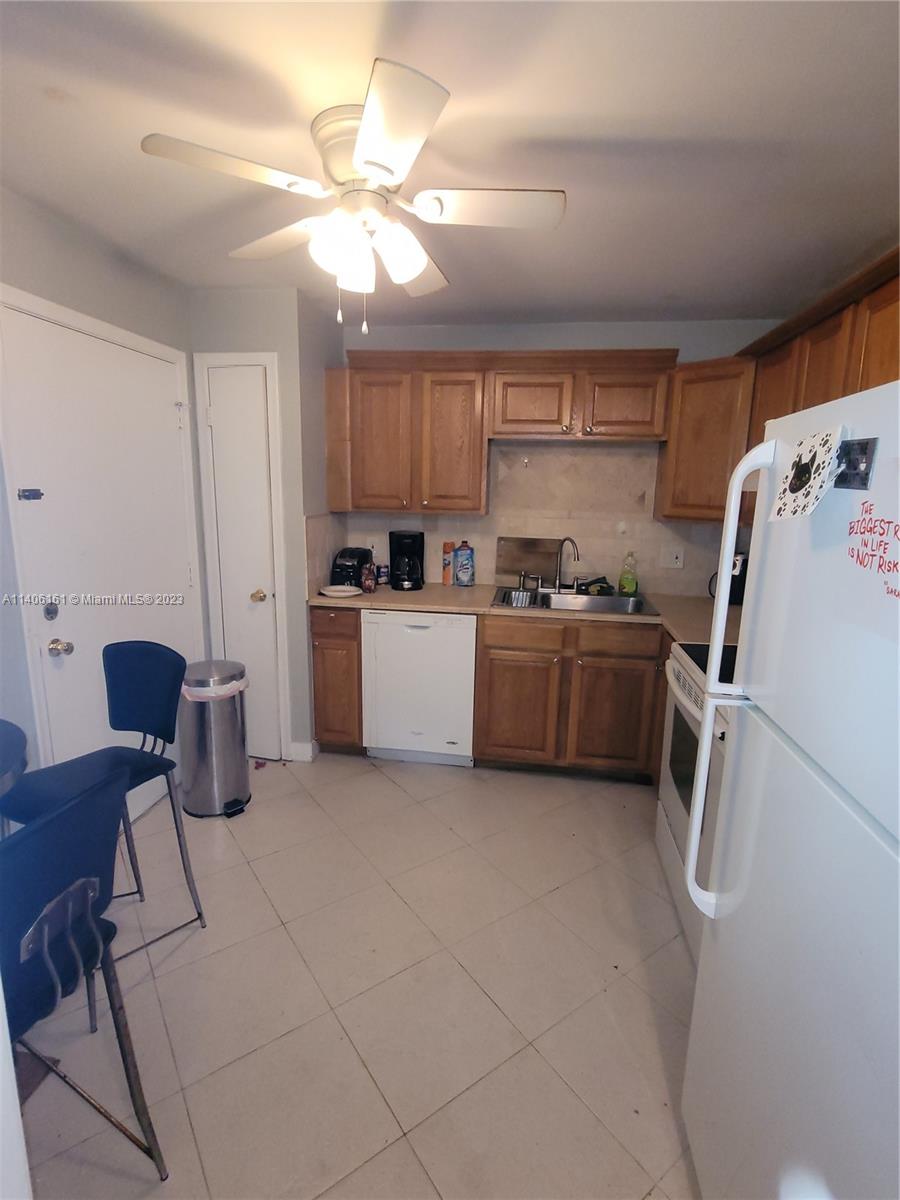 22605 Southwest 66th Avenue, Unit 207 Boca Raton, FL 33428 - Photo 10 of 15 a kitchen with a sink a stove cabinets and a dining table