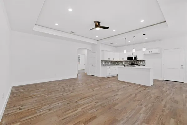 a view of kitchen with kitchen island a sink wooden floor and white stainless steel appliances