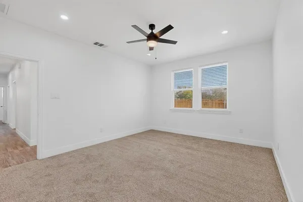 an empty room with a ceiling fan and windows