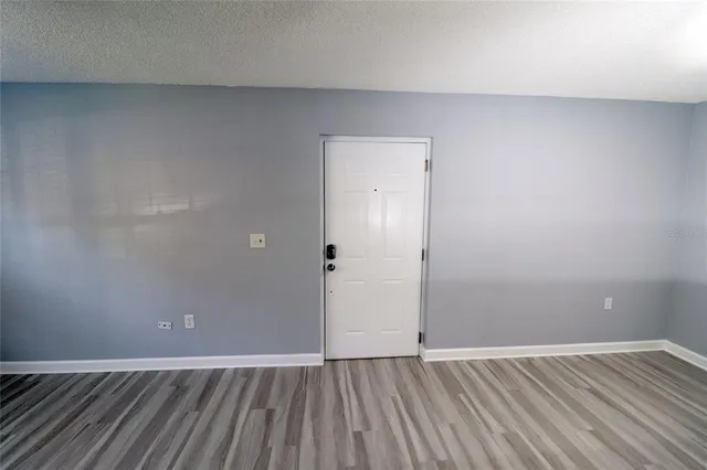 a view of an empty room with wooden floor and a bathroom