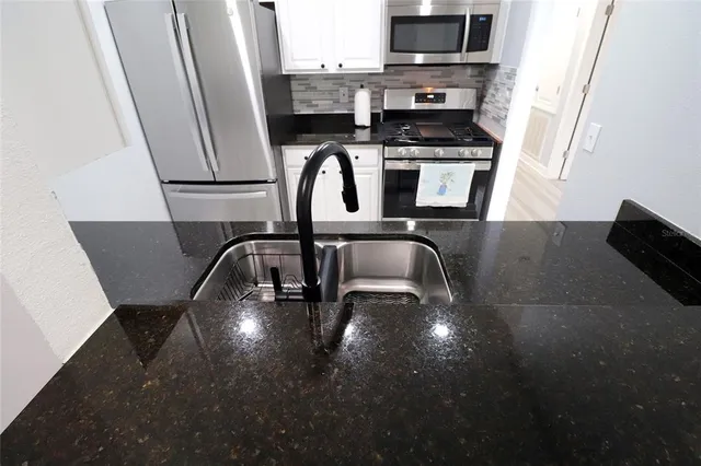 a kitchen with granite countertop a stove a sink and a microwave