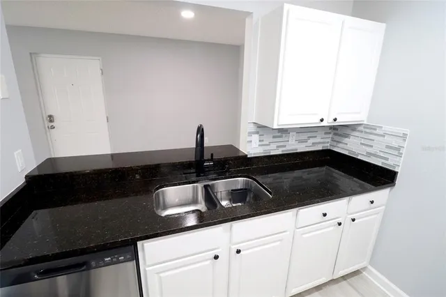 a kitchen with granite countertop a sink stove and cabinets