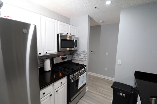 a kitchen with stainless steel appliances granite countertop a refrigerator and a stove top oven