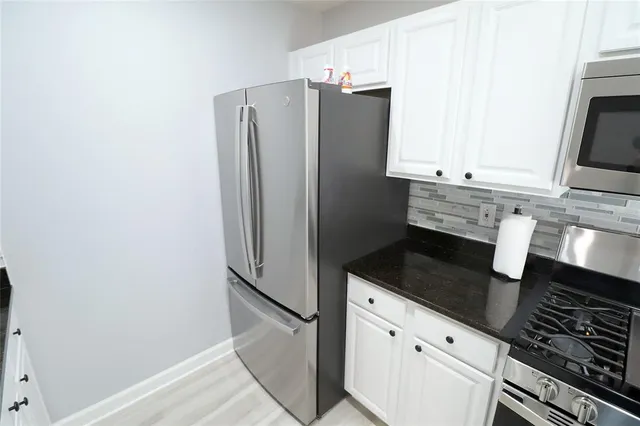 a kitchen with granite countertop white cabinets and stainless steel appliances