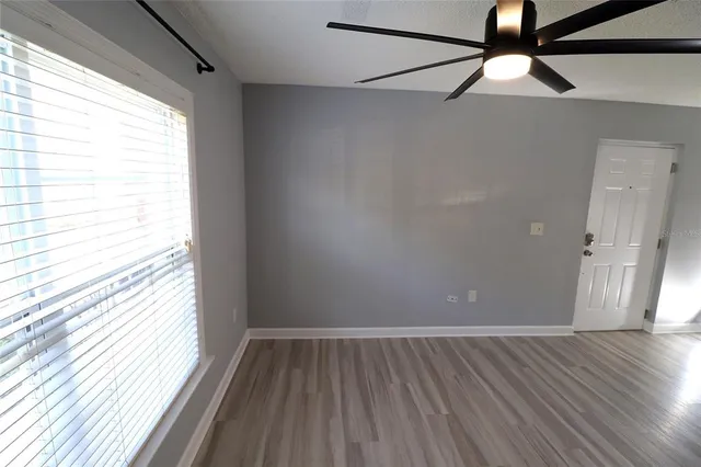 a view of an empty room with wooden floor and a window
