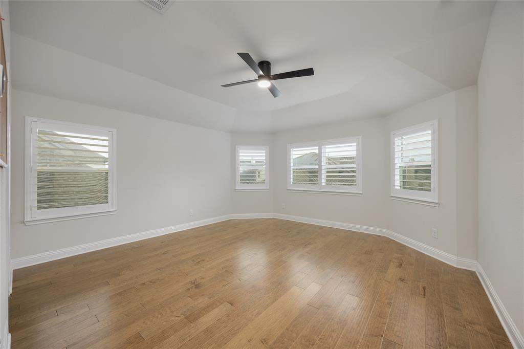 918 Sydney Lane Allen, TX 75013 - Photo 25 of 40 Bed room 3 featuring hardwood floors, a tray ceiling, and multiple windows with plantation shutters