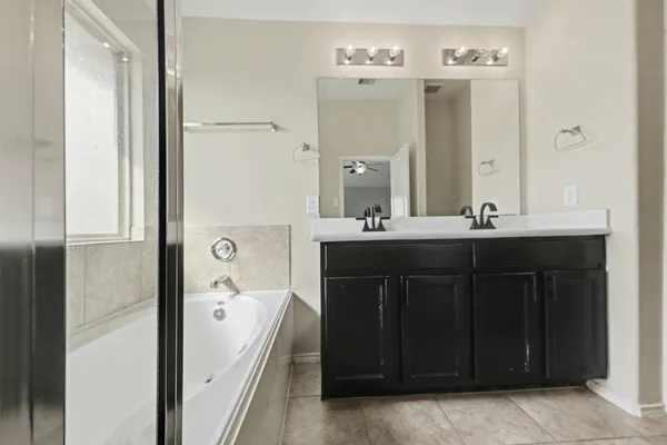a bathroom with a double vanity sink a mirror and a bathtub