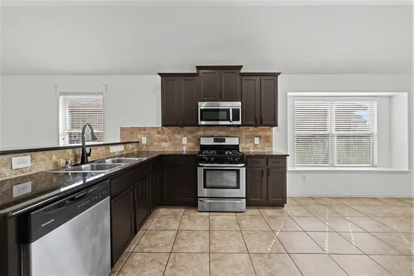a kitchen with kitchen island granite countertop a sink cabinets and stainless steel appliances