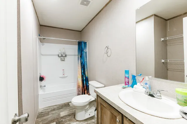 a view of a hallway with wooden floor and a bathroom