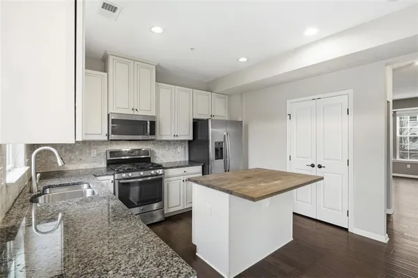 a kitchen with stainless steel appliances granite countertop a sink stove and refrigerator