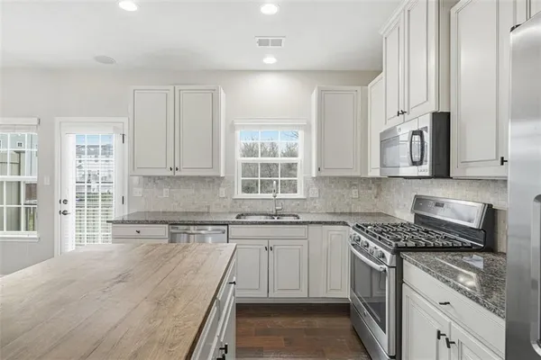 a kitchen with stainless steel appliances granite countertop a stove a sink and white cabinets