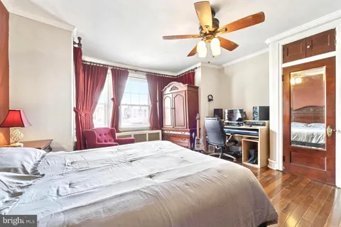 a bedroom with a bed dresser and a large window