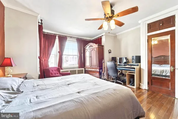a bedroom with a bed dresser and a large window