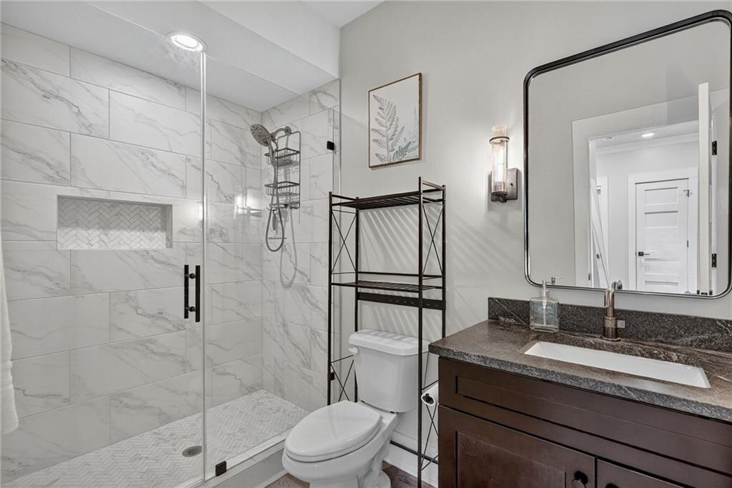 4621 Stanley Road Flowery Branch, GA 30542 - Photo 44 of 65 a bathroom with a granite countertop sink toilet and shower