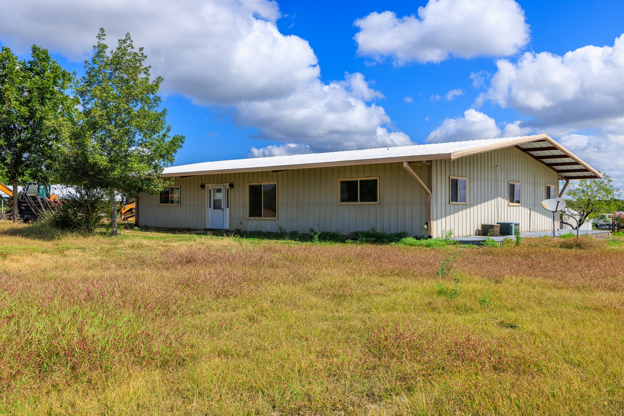 8804 Williamson Road Buda, TX 78610 - Photo 8 of 37 Metal siding and a shallow-pitch roof anchor this rural structure surrounded by open fields.