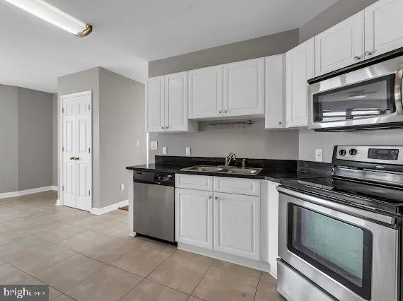 a kitchen with stainless steel appliances granite countertop white cabinets a stove a microwave and a sink