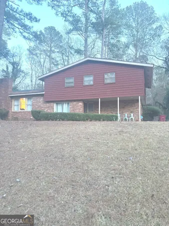 a front view of a house with a yard and a large tree