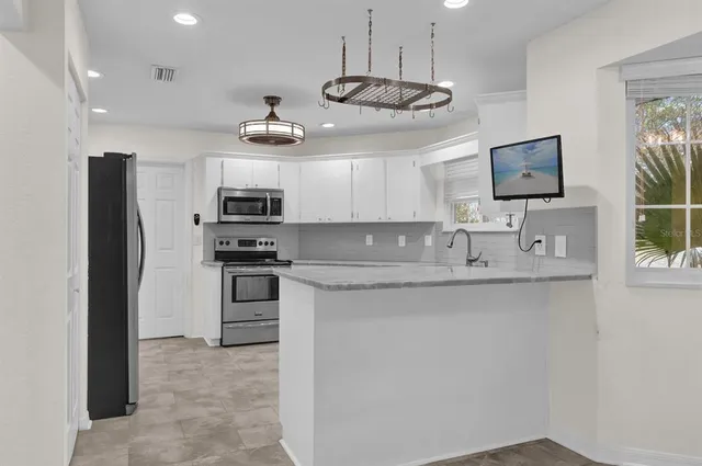 a kitchen with stainless steel appliances granite countertop a sink a stove and refrigerator