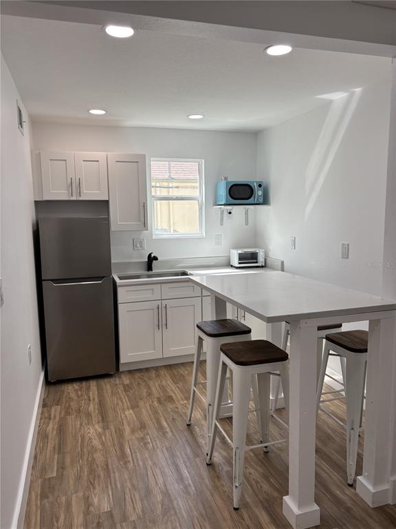 14141 Gulf Boulevard, Unit 5 Madeira Beach, FL 33708 - Photo 2 of 14 a kitchen with a sink a refrigerator a stove and white cabinets with wooden floor