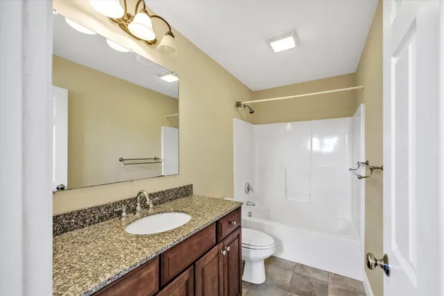 a bathroom with a granite countertop sink a toilet a mirror and shower