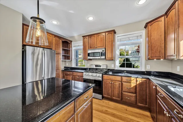 a kitchen with stainless steel appliances granite countertop a refrigerator a sink dishwasher a stove and white countertops with wooden floor