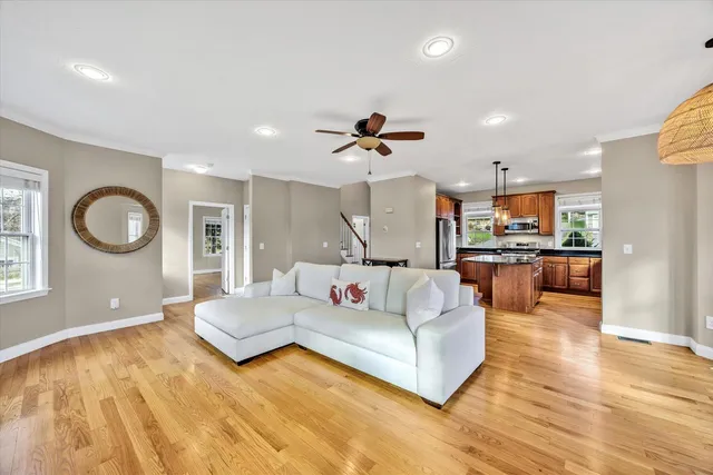 a living room with furniture kitchen view and a wooden floor