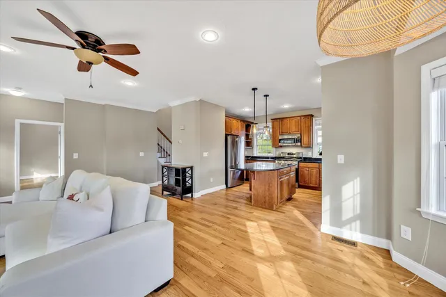 a living room with couches kitchen view and a refrigerator