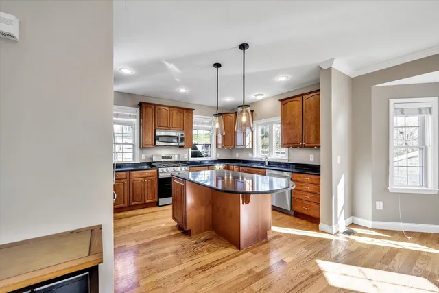 a large kitchen with stainless steel appliances kitchen island granite countertop a stove a sink and a refrigerator