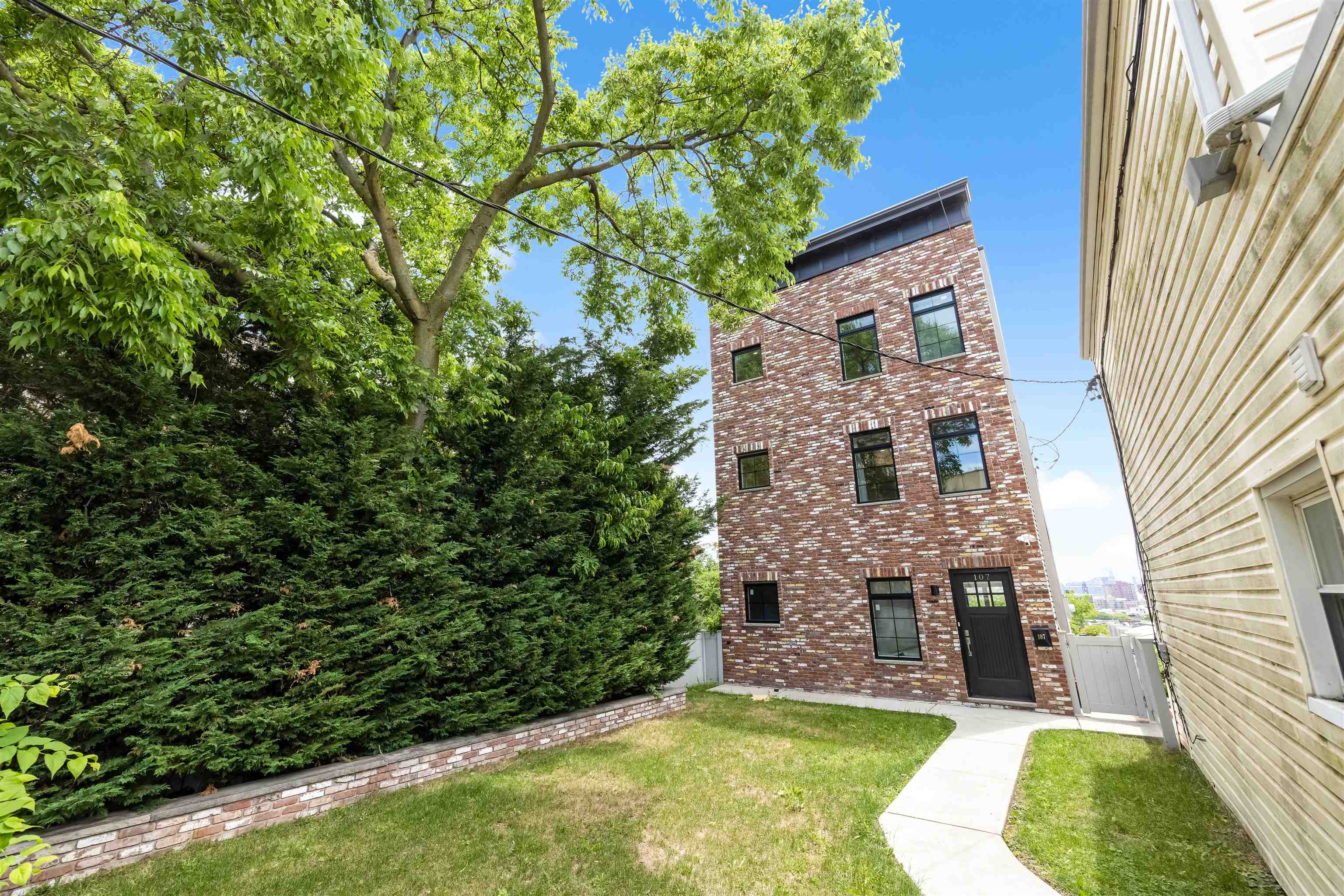 107 Mountain Road Jersey City, NJ 07307 - Photo 40 of 41 view of a brick house with a yard and plants