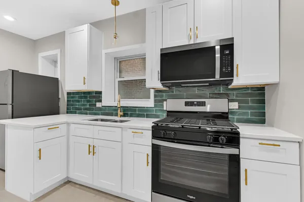 a kitchen with white cabinets and black appliances