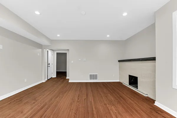an empty room with wooden floor and fireplace