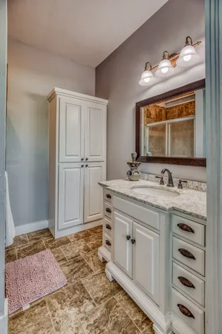a bathroom with a granite countertop sink and a mirror