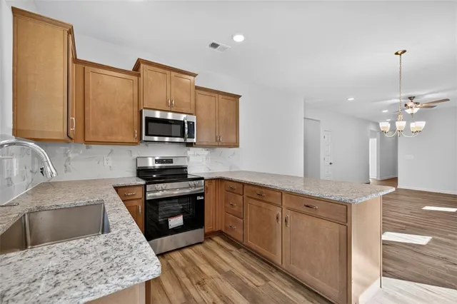 a kitchen with stainless steel appliances granite countertop a sink stove and microwave