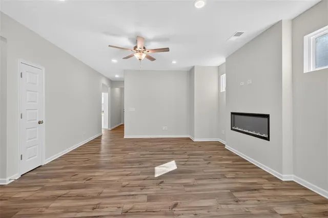 a view of empty room with wooden floor and ceiling fan