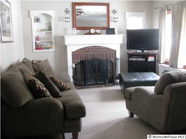 129 Pond Road Freehold, NJ 07728 - Photo 3 of 3 a living room with furniture a flat screen tv and a fireplace