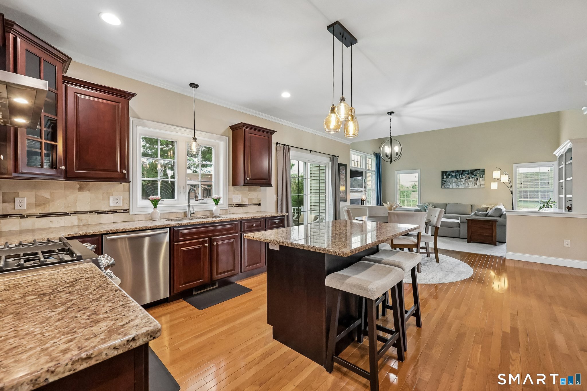2 Gatehouse Road Granby, CT 06035 - Photo 12 of 40 a open kitchen with stainless steel appliances granite countertop a stove top oven a dining table and chairs with wooden floor