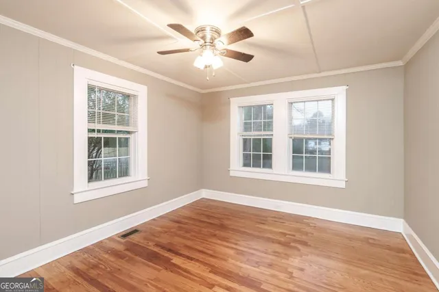 an empty room with wooden floor and windows