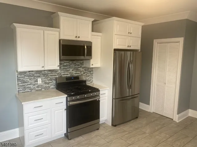 a kitchen with granite countertop a refrigerator stove and microwave