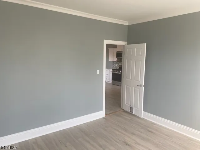 a view of an empty room with wooden floor and closet