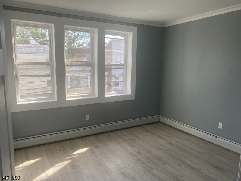 14 Jackson Street, Unit 9 Passaic, NJ 07055 - Photo 7 of 11 a view of an empty room with wooden floor and a window