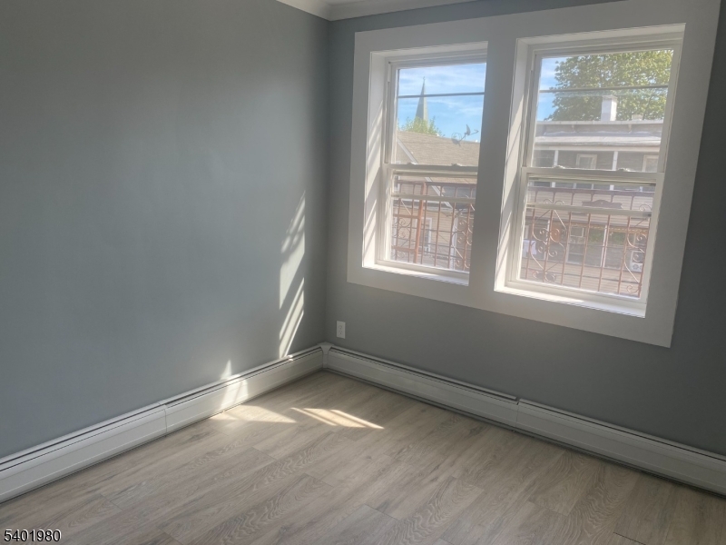 14 Jackson Street, Unit 9 Passaic, NJ 07055 - Photo 9 of 11 an empty room with wooden floor and windows
