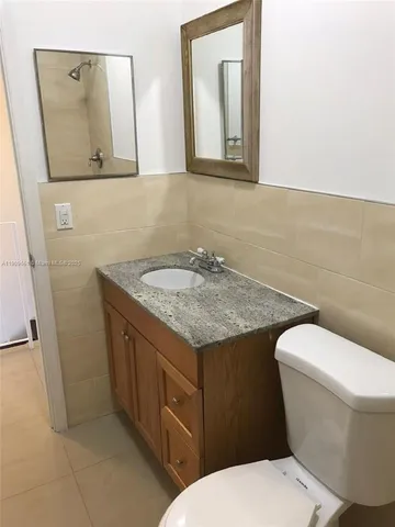 a bathroom with a granite countertop toilet sink and mirror
