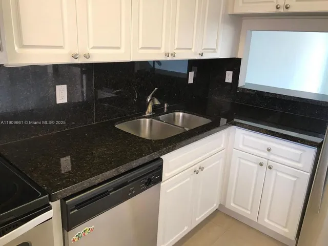 a kitchen with granite countertop white cabinets and sink