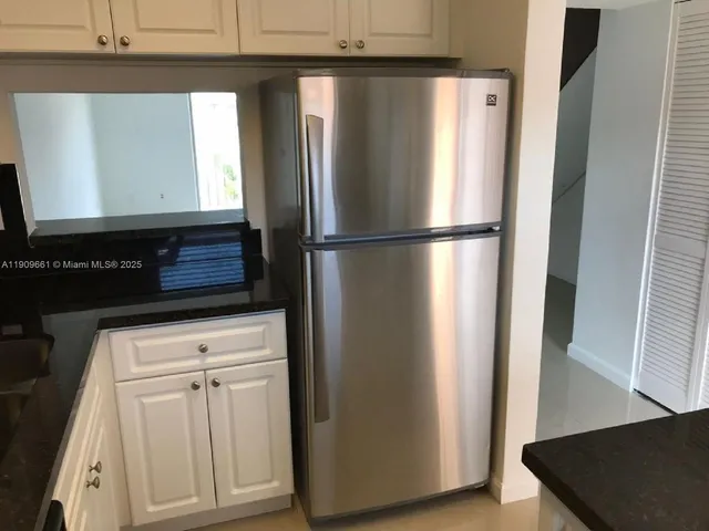 a view of a refrigerator in kitchen and dishwasher with wooden floor