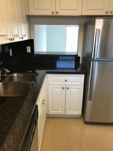 a kitchen with granite countertop a sink and a refrigerator