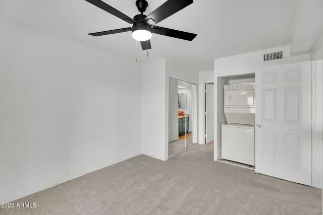 an empty room with closet and a ceiling fan
