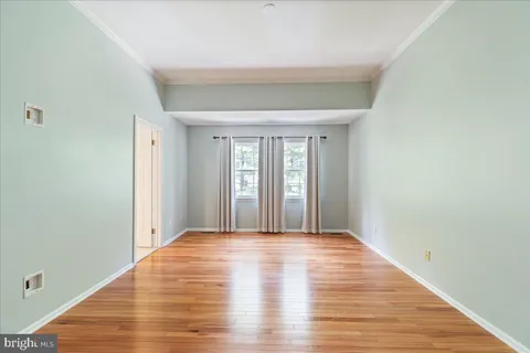 a view of a big room with wooden floor and windows