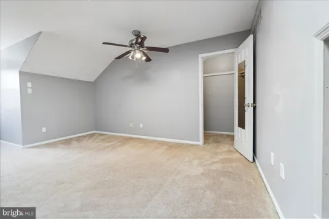 an empty room with a chandelier fan and windows